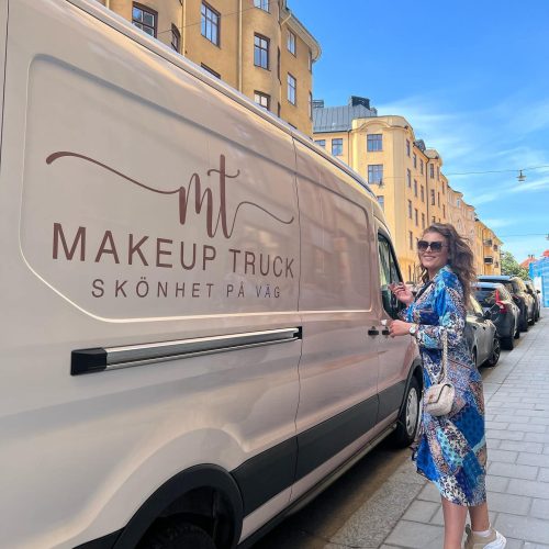 Makeup Truck insida Karoline stående bredvid bilen i blå klänning