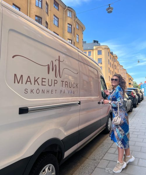 Makeup Truck insida Karoline stående bredvid bilen i blå klänning
